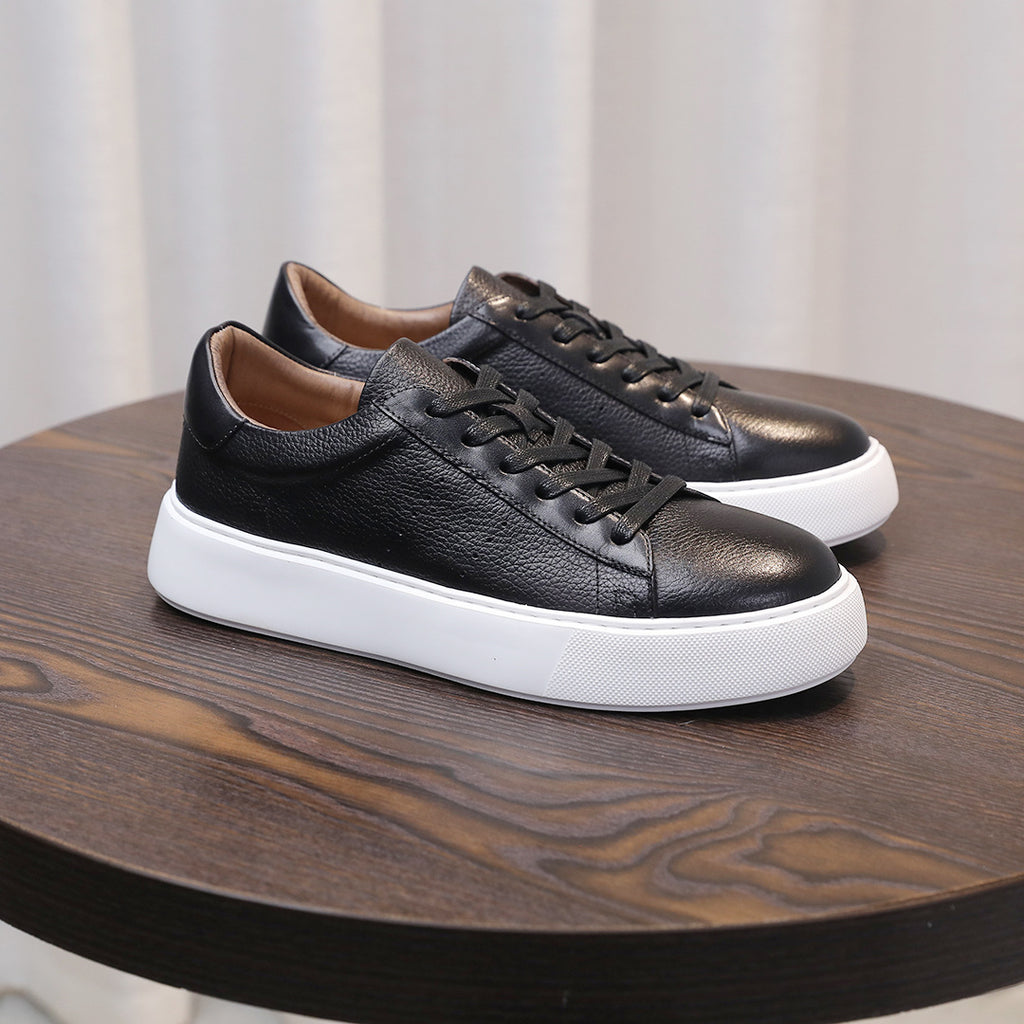 Black leather low-top sneakers with lace-up front and white rubber sole.