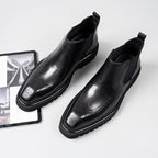 Black leather Chelsea dress boots with perforated toe and elastic side gore panels