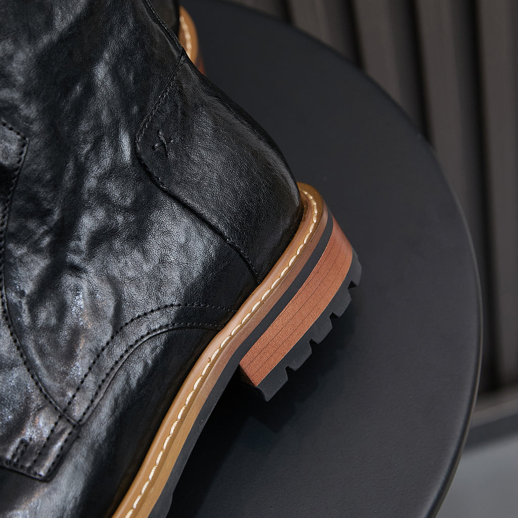 Black leather boot heel and side seam with pointed toe and tan welt.