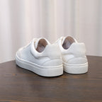 Men's white leather sneakers, rear view with lace-up closure and cushioned heel