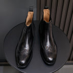 Pair of men's pointed-toe black chelsea boots with elastic sides and pull tabs