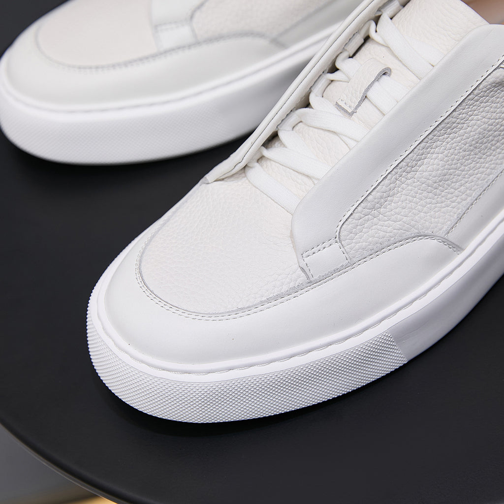 Close-up of white genuine leather low-top sneaker with laces and textured rubber sole