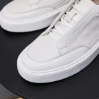 Close-up of white genuine leather low-top sneaker with laces and textured rubber sole