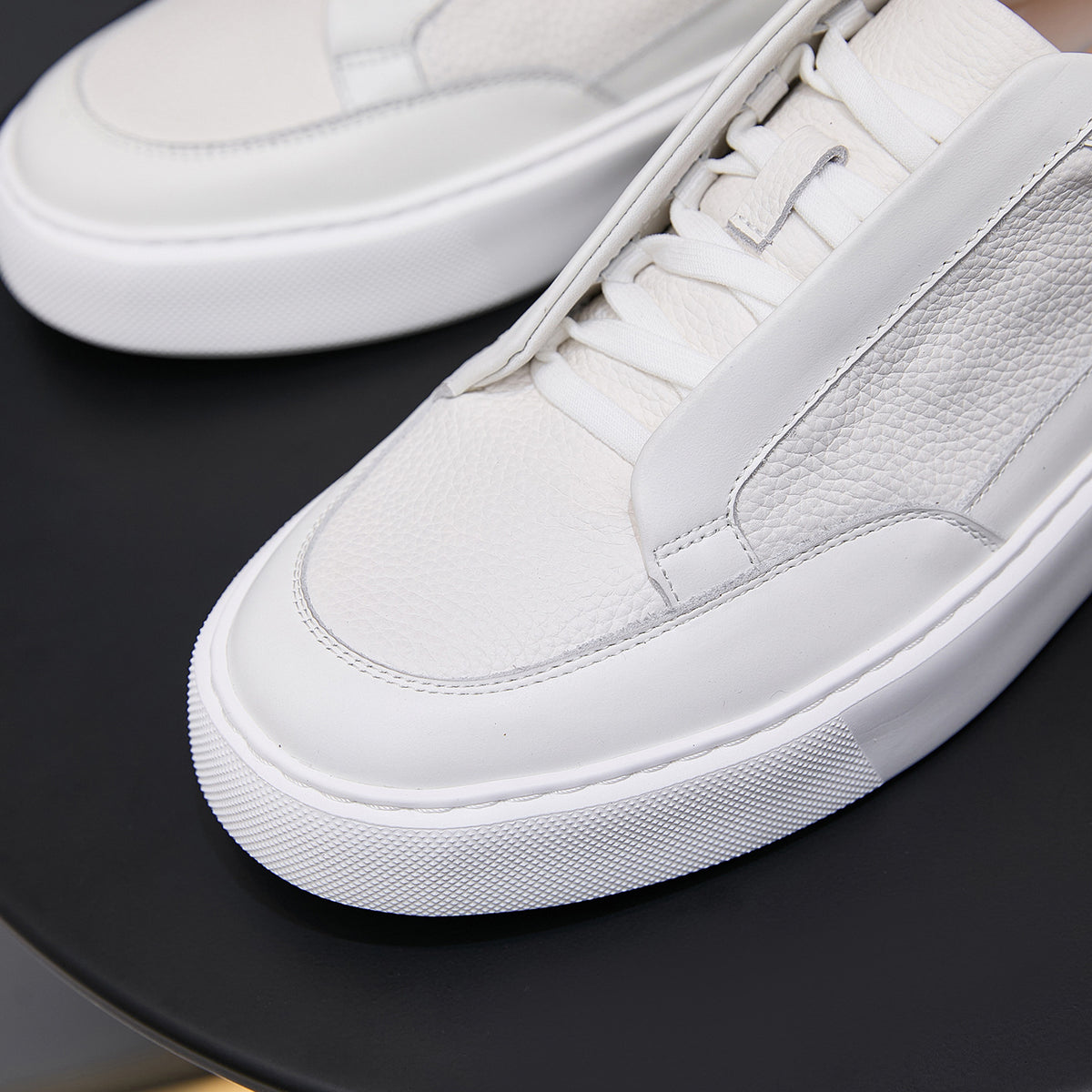 Close-up of white genuine leather low-top sneaker with laces and textured rubber sole
