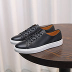 Men's leather sneakers, black low-top lace-up with white rubber sole trim.