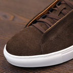 Close-up of brown suede leather sneaker toe with lace and textured white sole