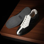 Black and white leather sneakers showing textured rubber outsole tread.