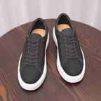 Pair of black leather low-top sneakers with purple-gray laces and white sole