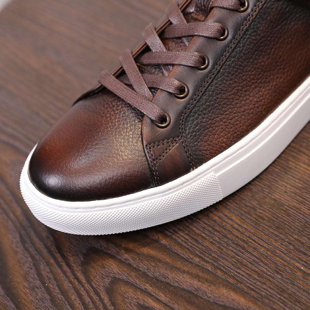 Men's dark brown leather sneaker close-up with lace-up front and white midsole