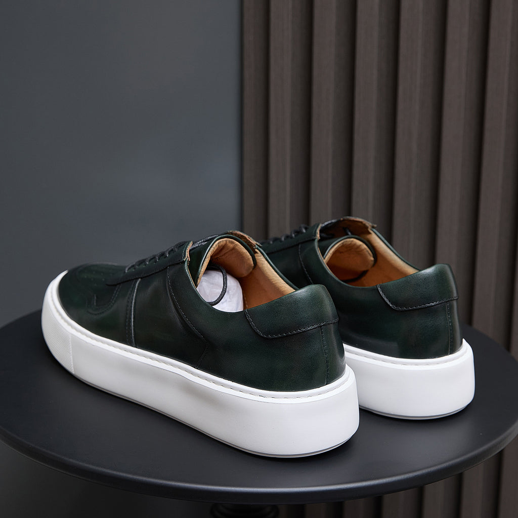 Leather sneakers rear view, dark green uppers with heel tabs and white rubber sole.