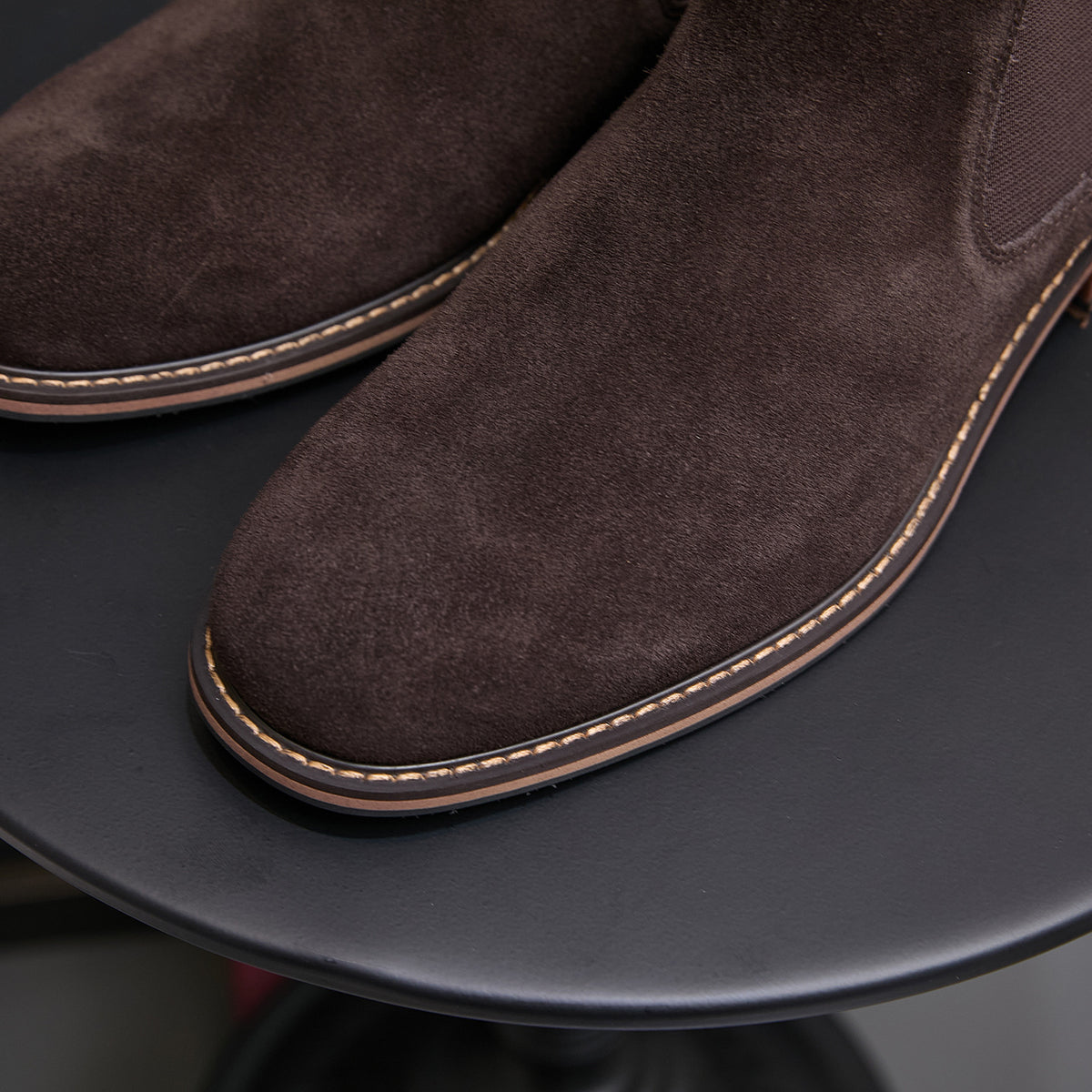Close-up of dark brown suede Chelsea dress boot toe and stitched welt edge