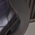 Leather boot quarter panel with side brogue stitching and dark rubber sole, dark blue.