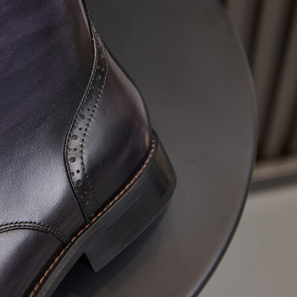Leather boot quarter panel with side brogue stitching and dark rubber sole, dark blue.