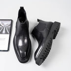 Black leather Chelsea dress boots showing treaded sole and elastic side gore panels