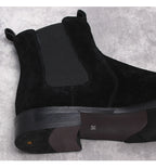 Black suede Chelsea boots close-up, elastic gore and textured midsole detail