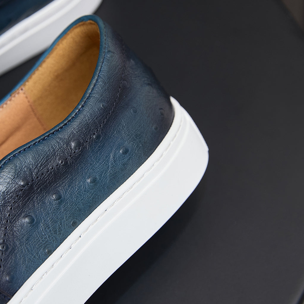 Men's blue leather sneaker side close-up with white sole and embossed texture