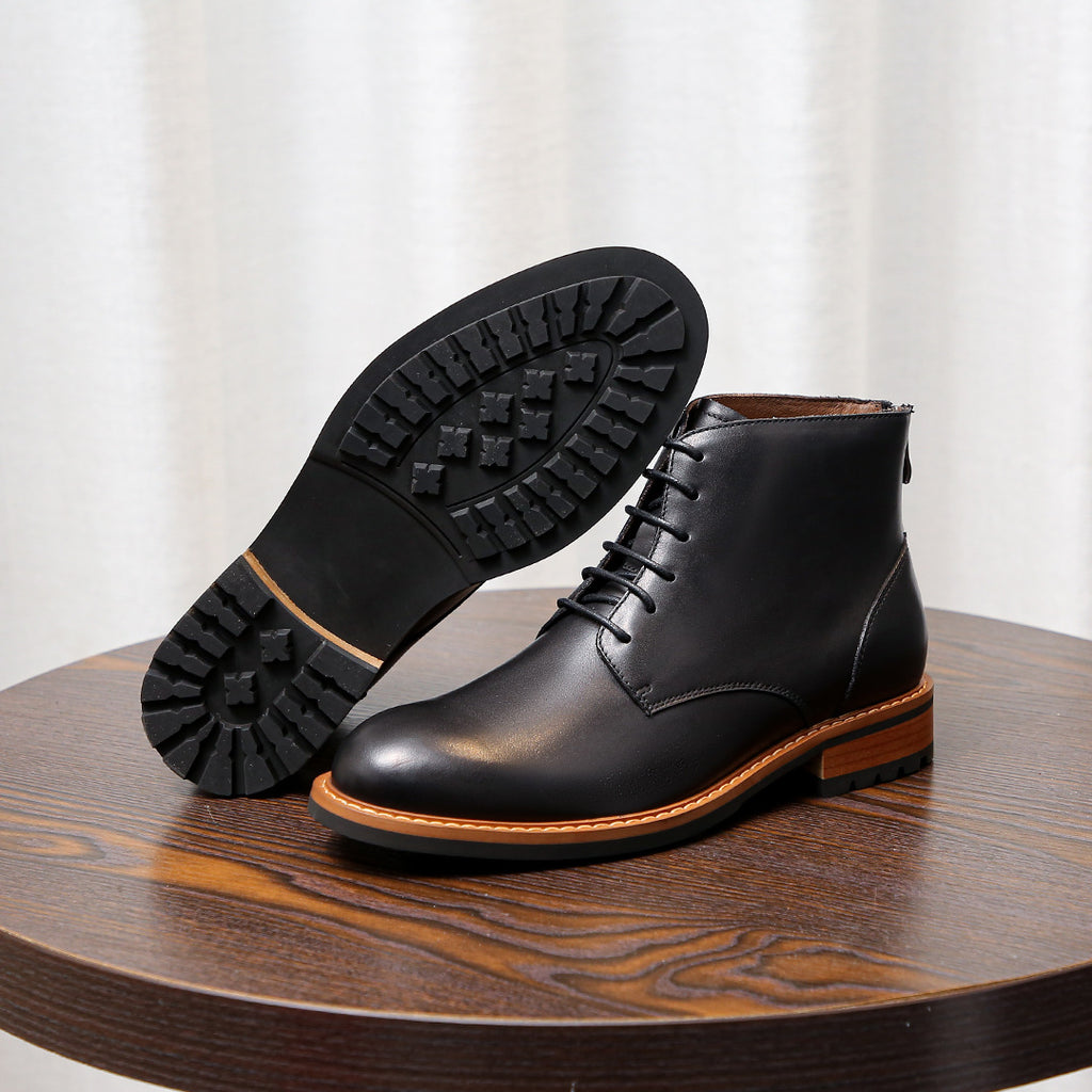 Black leather lace-up boots showing rubber outsole tread and orange welt edge