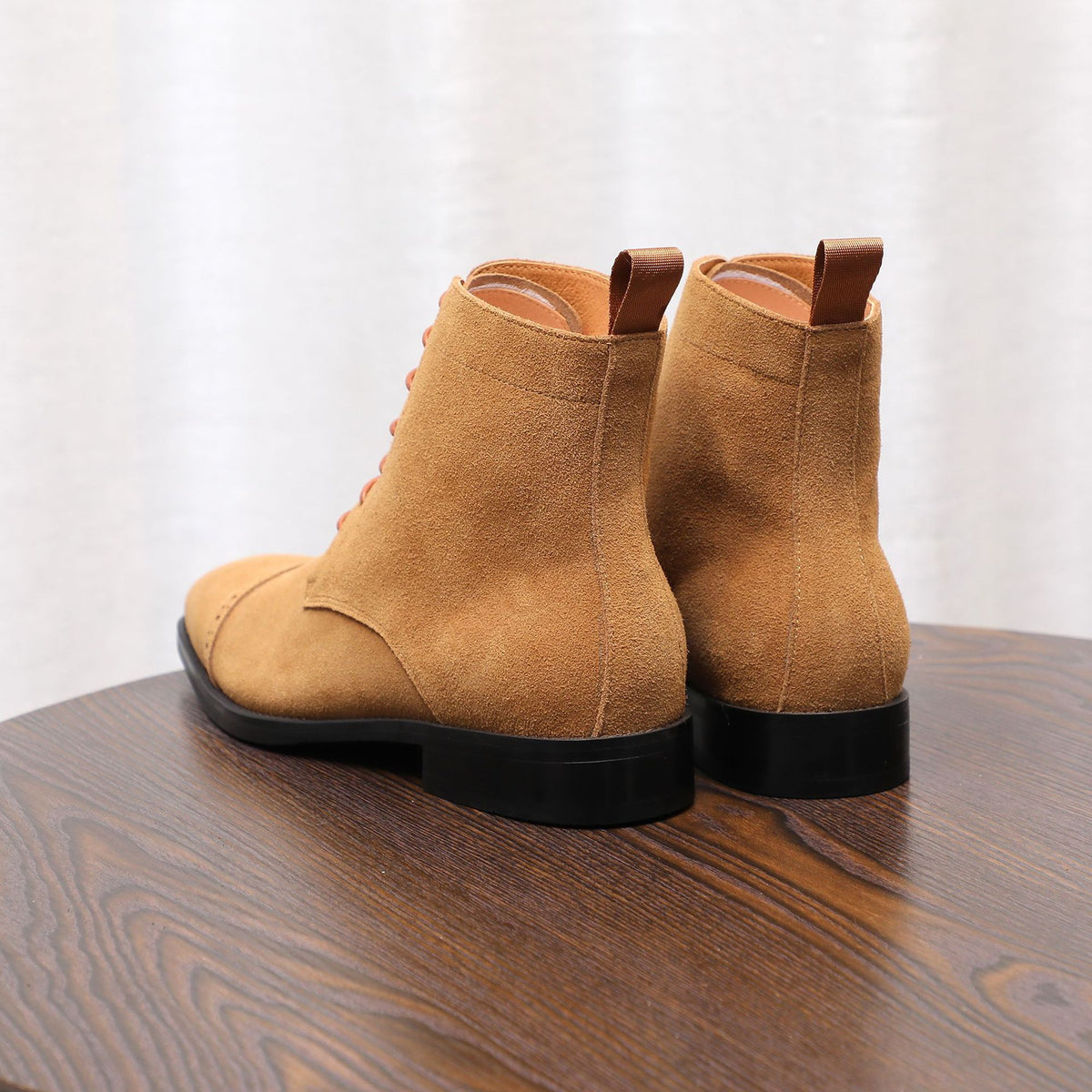 Pair of tan suede chukka boots, back view with pull tab and black outsole