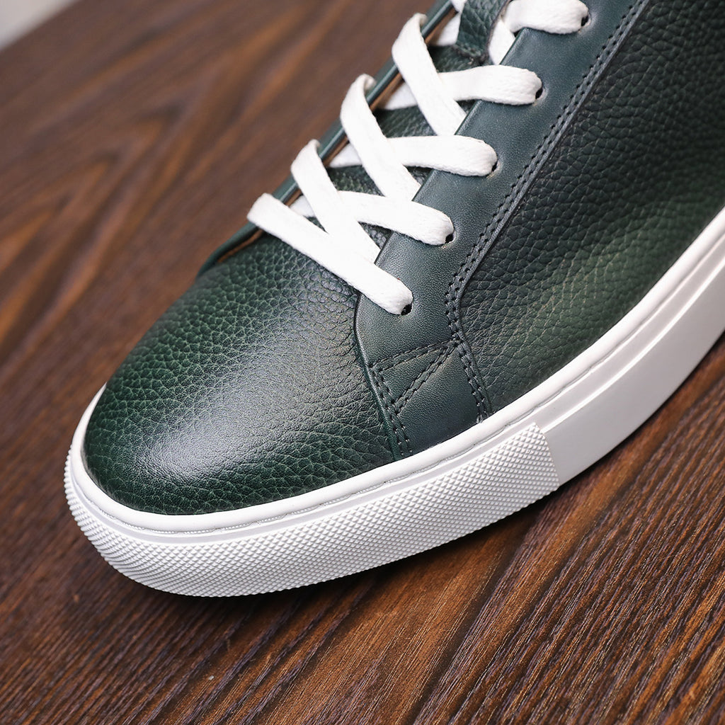 Close-up of green leather lace-up sneakers with white stitching and white rubber sole