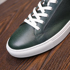 Close-up of green leather lace-up sneakers with white stitching and white rubber sole