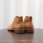 Back view of tan-brown suede lace-up chukka boots with heel and ankle pull tabs.