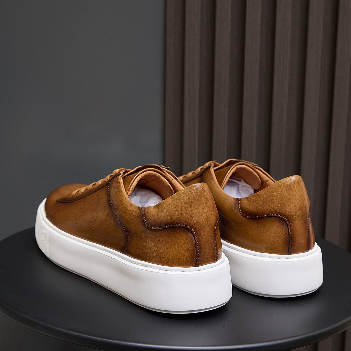 Men's brown leather slip-on style sneakers shown from heel and back, white sole