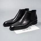 Black leather Chelsea dress boots with elastic gore, perforated toe, and low block heel
