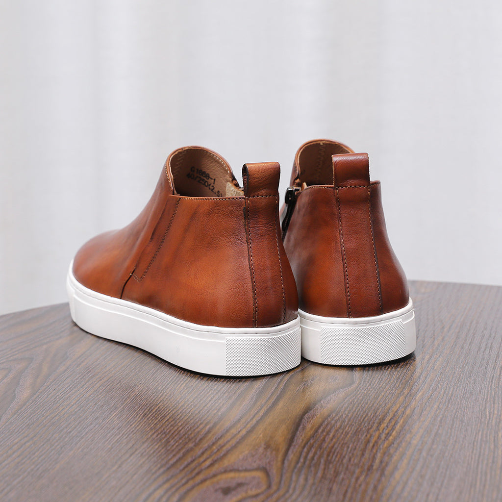 Brown leather pointed-toe dress boots with side zippers and white rubber soles
