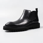 Black leather Chelsea dress boot with elastic gore, perforated toe, and chunky outsole