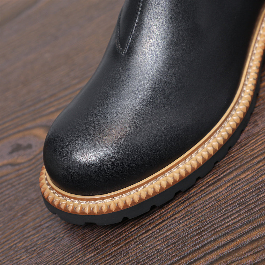 Close-up of black pointed toe Chelsea boot with tan welt trim and grippy sole