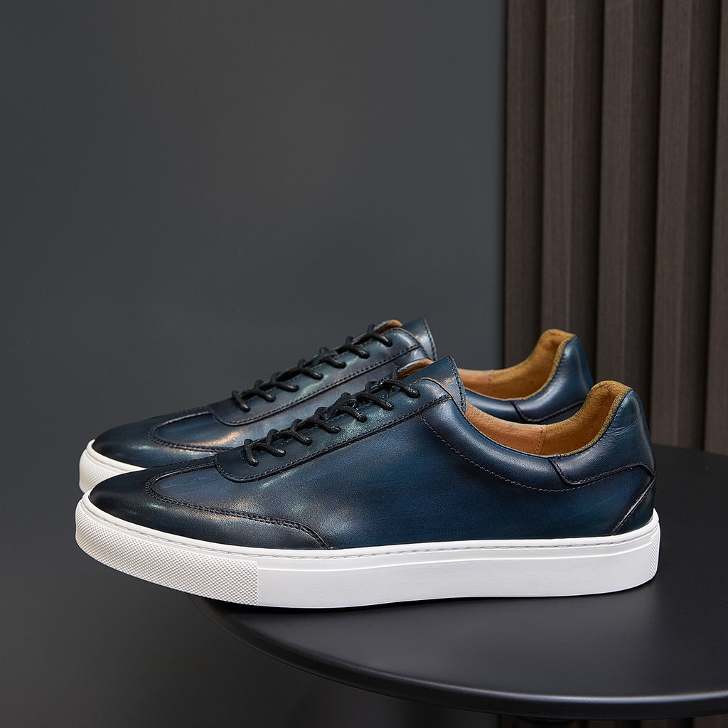 Men's leather sneakers in deep blue with black laces, white sole, and tan lining.