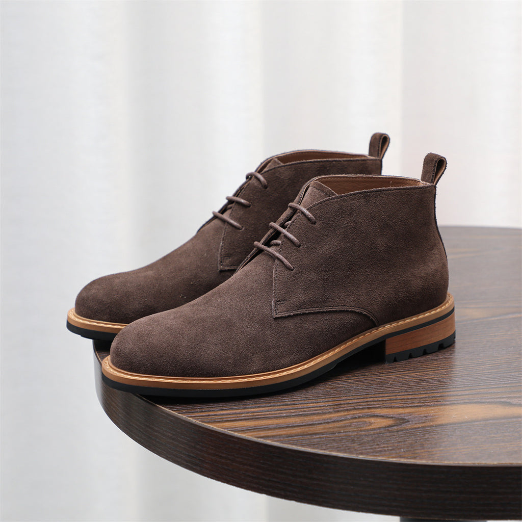 Pair of dark brown suede lace-up chukka boots with low heel and textured sole.
