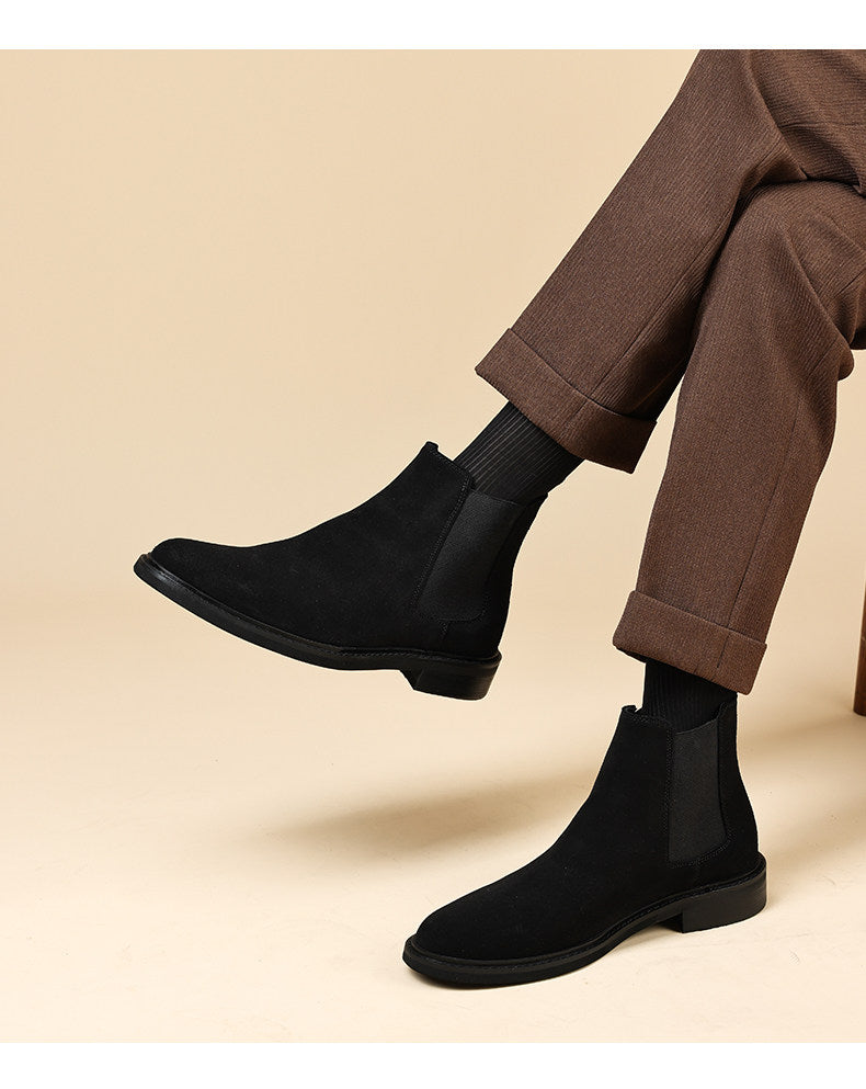 Black Chelsea dress boots on feet with elastic side panels and low stacked heel.