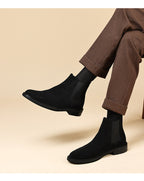 Black Chelsea dress boots on feet with elastic side panels and low stacked heel.