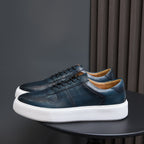 Leather sneakers, dark blue-green, lace-up front with white rubber sole.