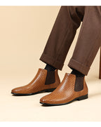 Brown woven leather chelsea boots with side elastic panels worn with dark pants