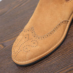 Close-up of brown suede pointed toe with brogue-style perforation and rubber sole edge