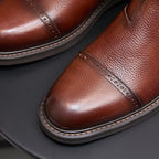 Brown Chelsea dress boots close-up: pointed toe stitching and perforated side detail