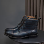 Pair of lace-up leather dress boots, dark blue with pointed toe and stacked heel sole.