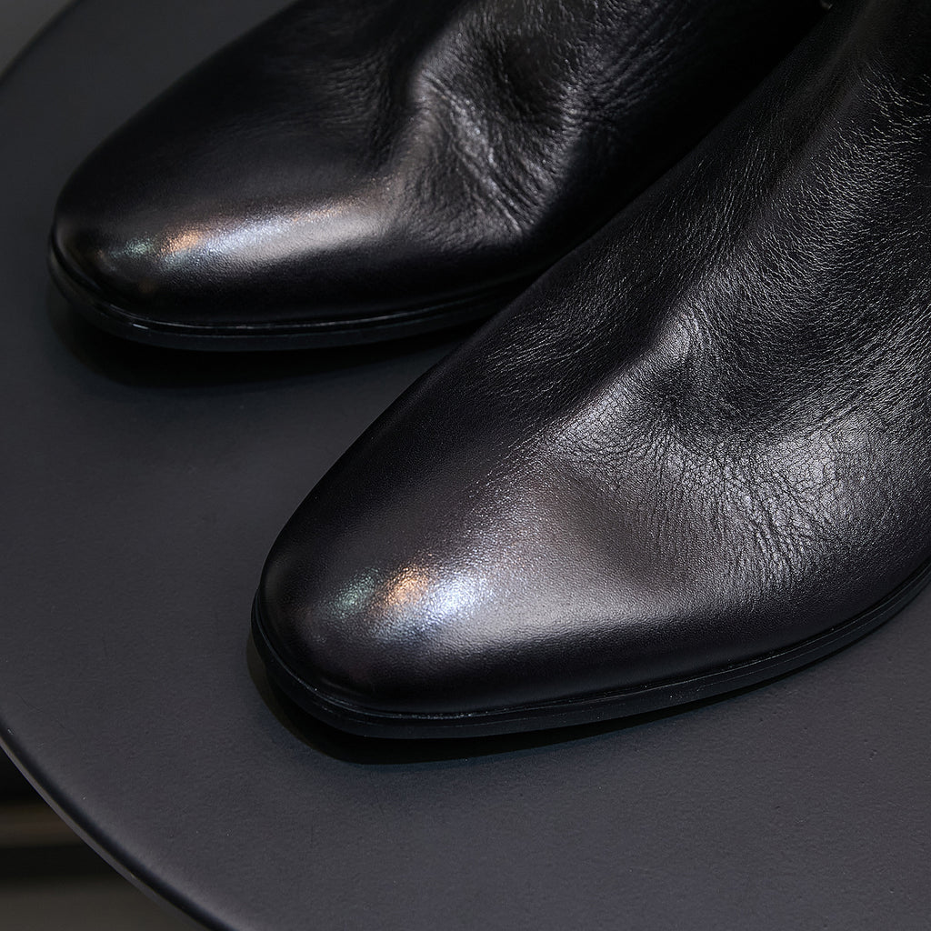 Black pointed-toe Chelsea dress boots close-up, smooth upper and toe detail
