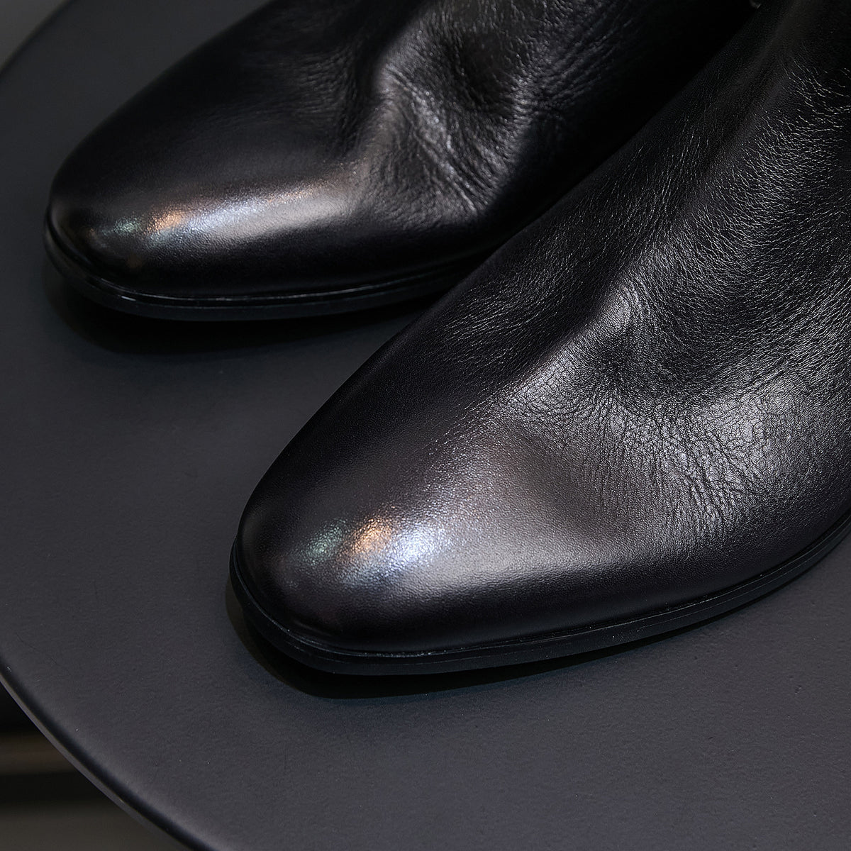 Black pointed-toe Chelsea dress boots close-up, smooth upper and toe detail