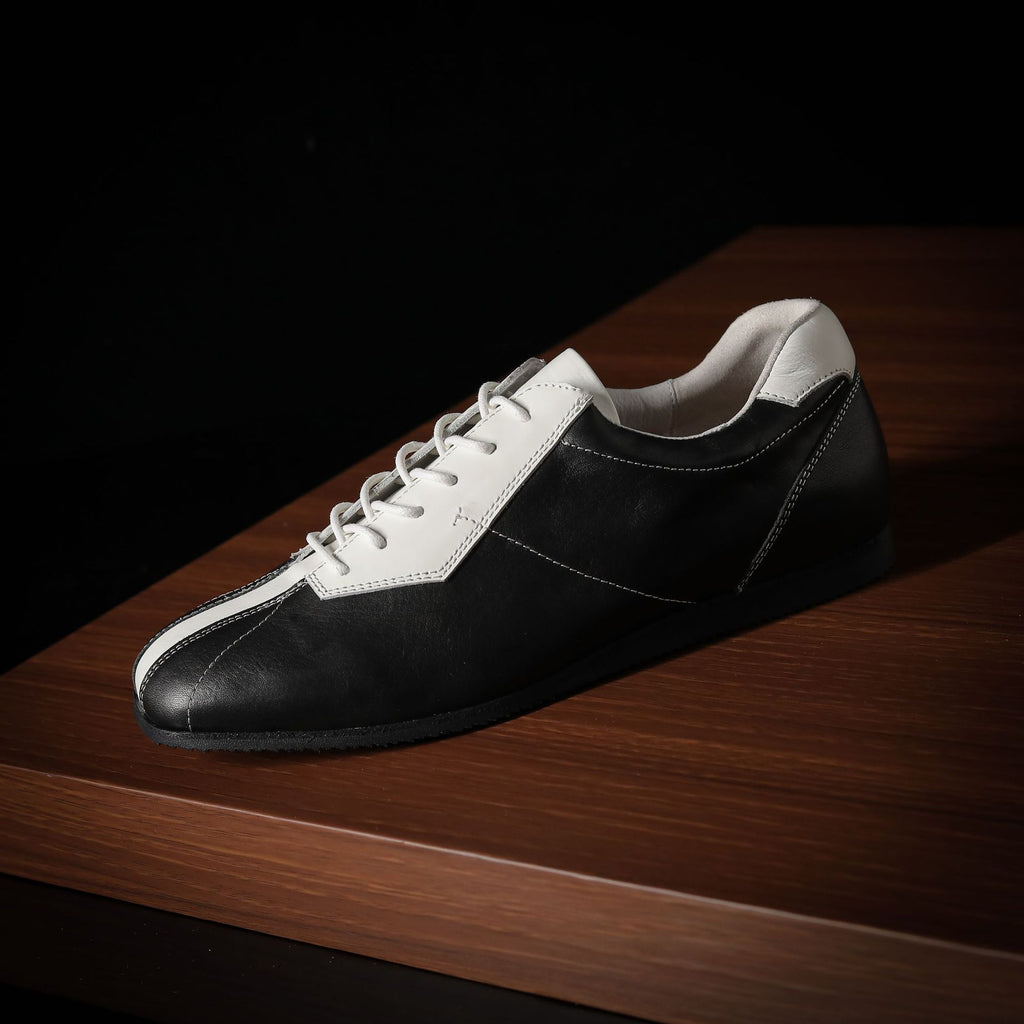 Black and white leather sneaker with lace-up front and contrasting side panel stripe.