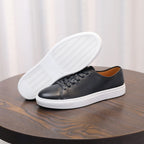 Black leather sneakers with white rubber sole and lace-up front.
