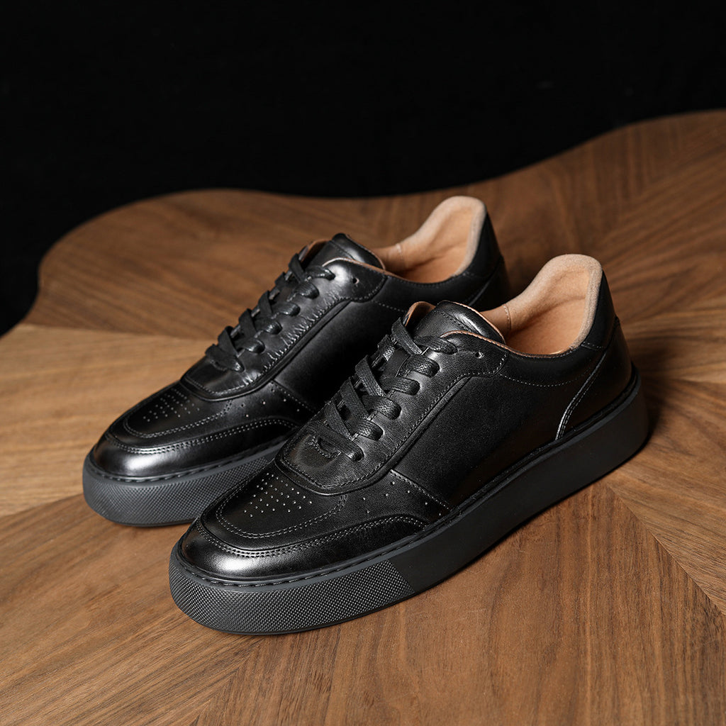 Black leather sneakers with lace-up front and perforated toe, chunky outsole.