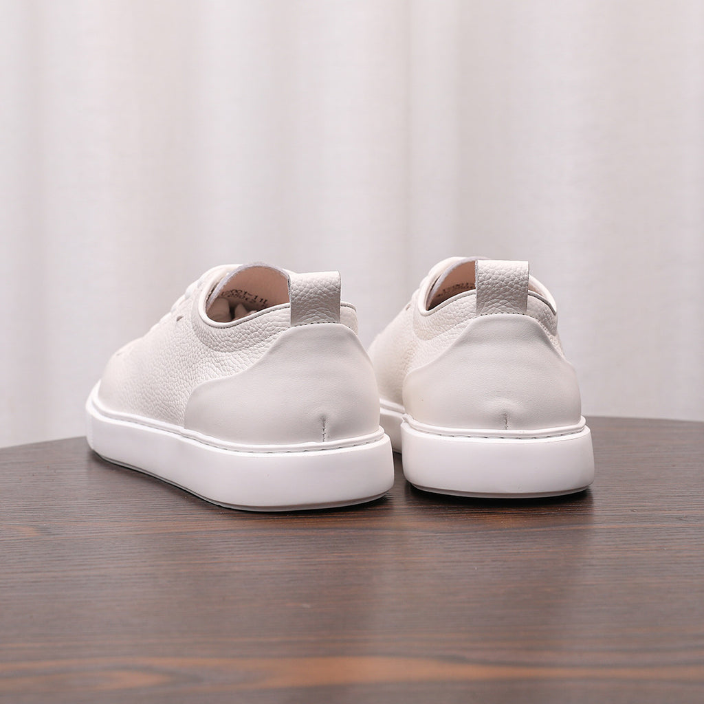 White leather low-top sneakers with lace-up front and thick white rubber sole