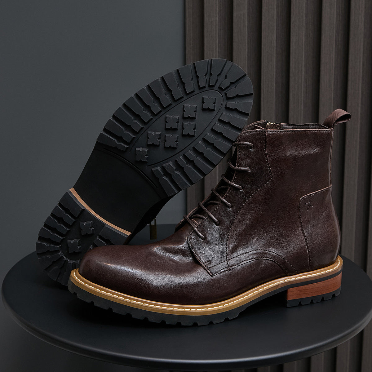 Dark brown leather cap-toe boots with side zip and lace-up; outsole tread visible