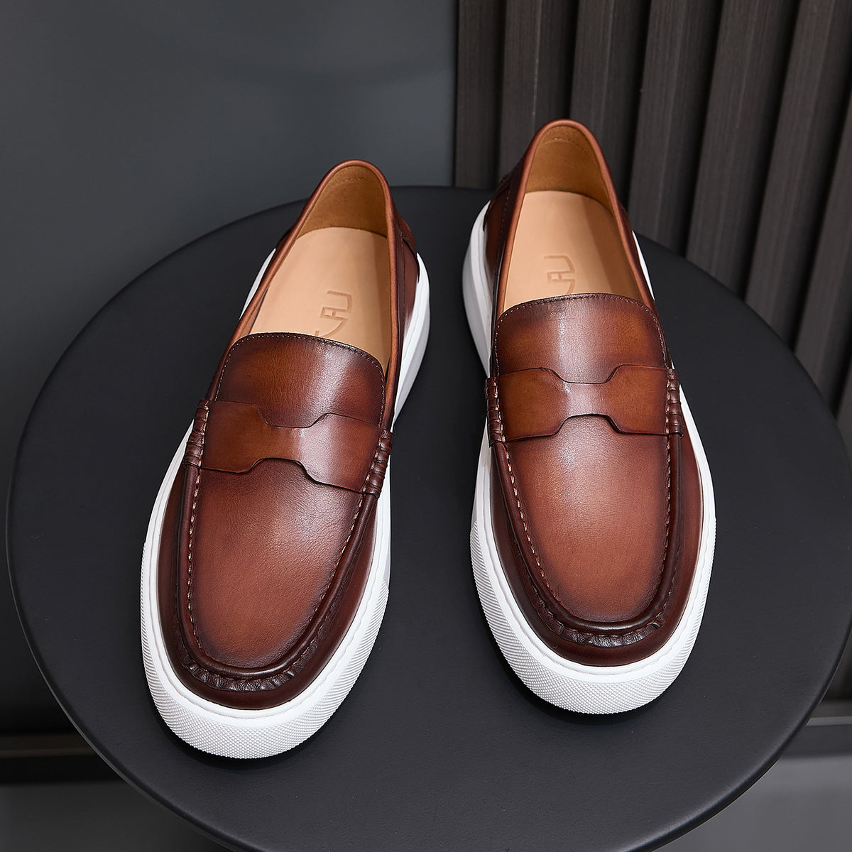 Pair of brown leather slip-on sneakers with moccasin seam detailing and white platform sole