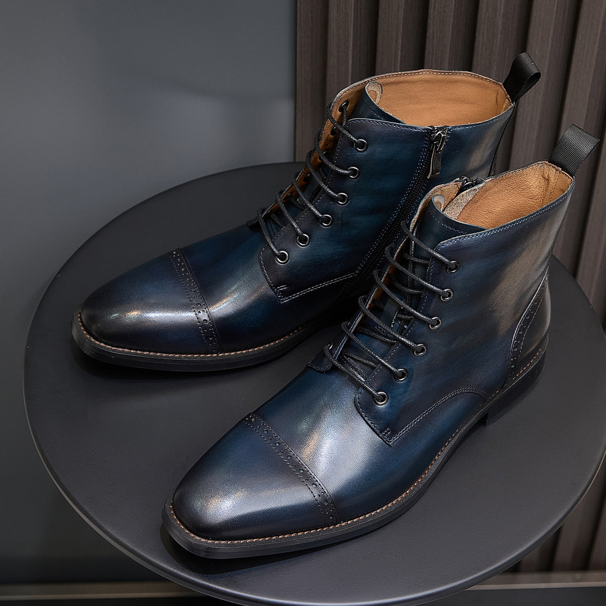 Lace-up leather dress boots, dark blue with pointed toe, apron stitching, and brown welt.