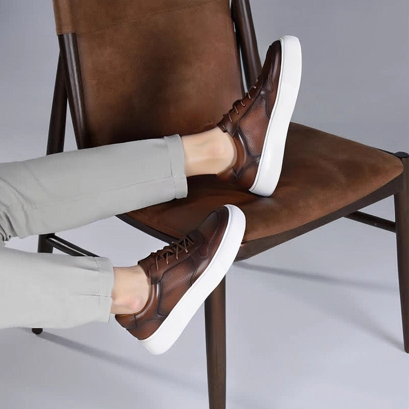 Men's brown leather sneakers with white sole, worn with light gray pants