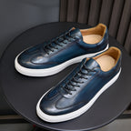 Pair of men's blue leather sneakers with black laces and white rubber soles.